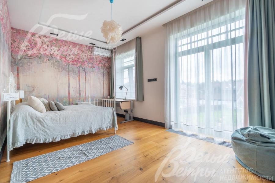 Одна из спален на втором этаже с большим окном в пол и полным комплектом мебели