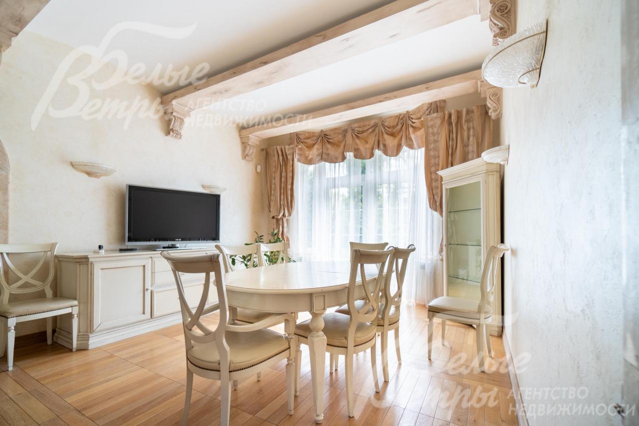 Столовая с обеденной группой, мебелью и телевизором. Большое окно наполняет гостиную дневным светом