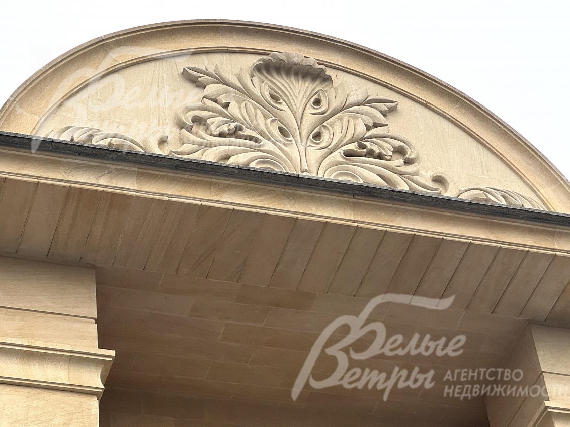В центре фасада расположено декоративное панно ручной работы из камня
