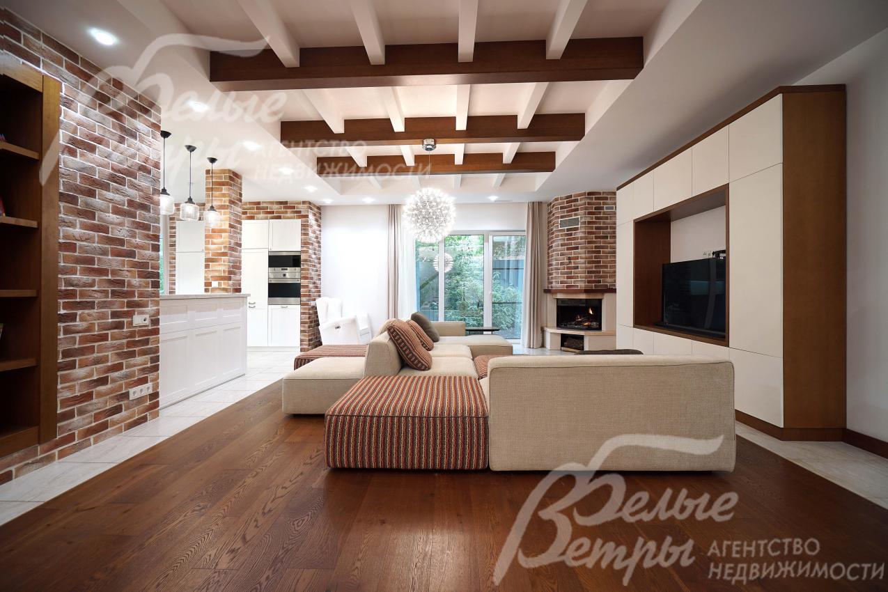 Гостиная с акцентными стенами с отделкой "под кирпич" и декоративными деревянными балками на потолке