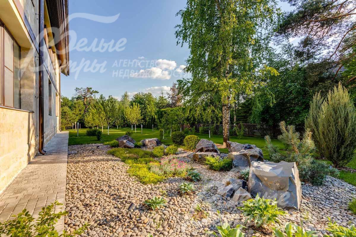 На участке множество деревьев, декоративных кустарников и цветников