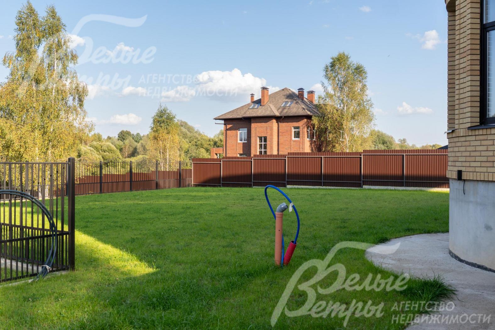 Дом стоит на просторном благоустроенном участке с газоном и садовыми дорожками