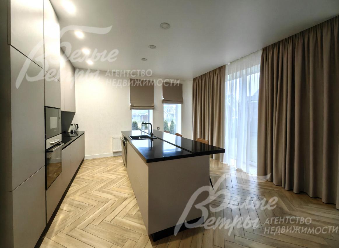 Кухонный гарнитур с островом и барными стульями.