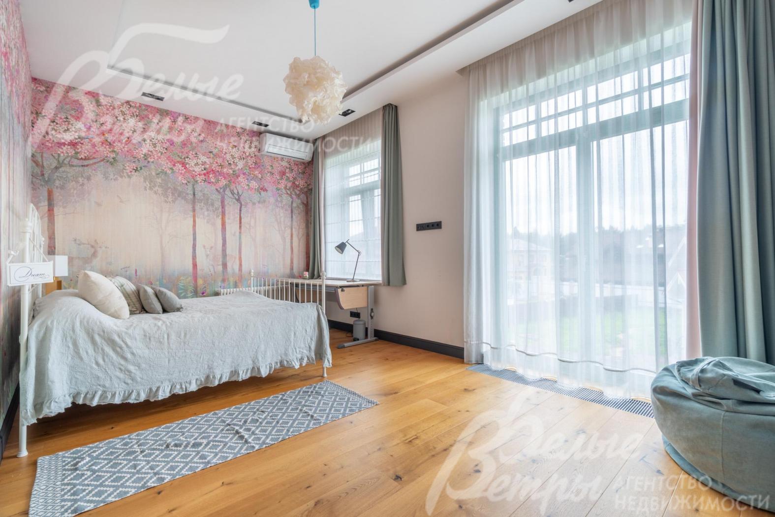 Одна из спален на втором этаже с большим окном в пол и полным комплектом мебели