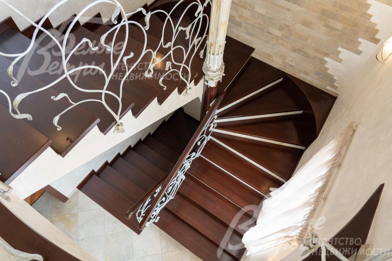 Эффектная лестница шириной 140 см с монолитным каркасом и дубовыми ступенями (подступенки - керамогранит). Ограждение лестницы - художественная ковка