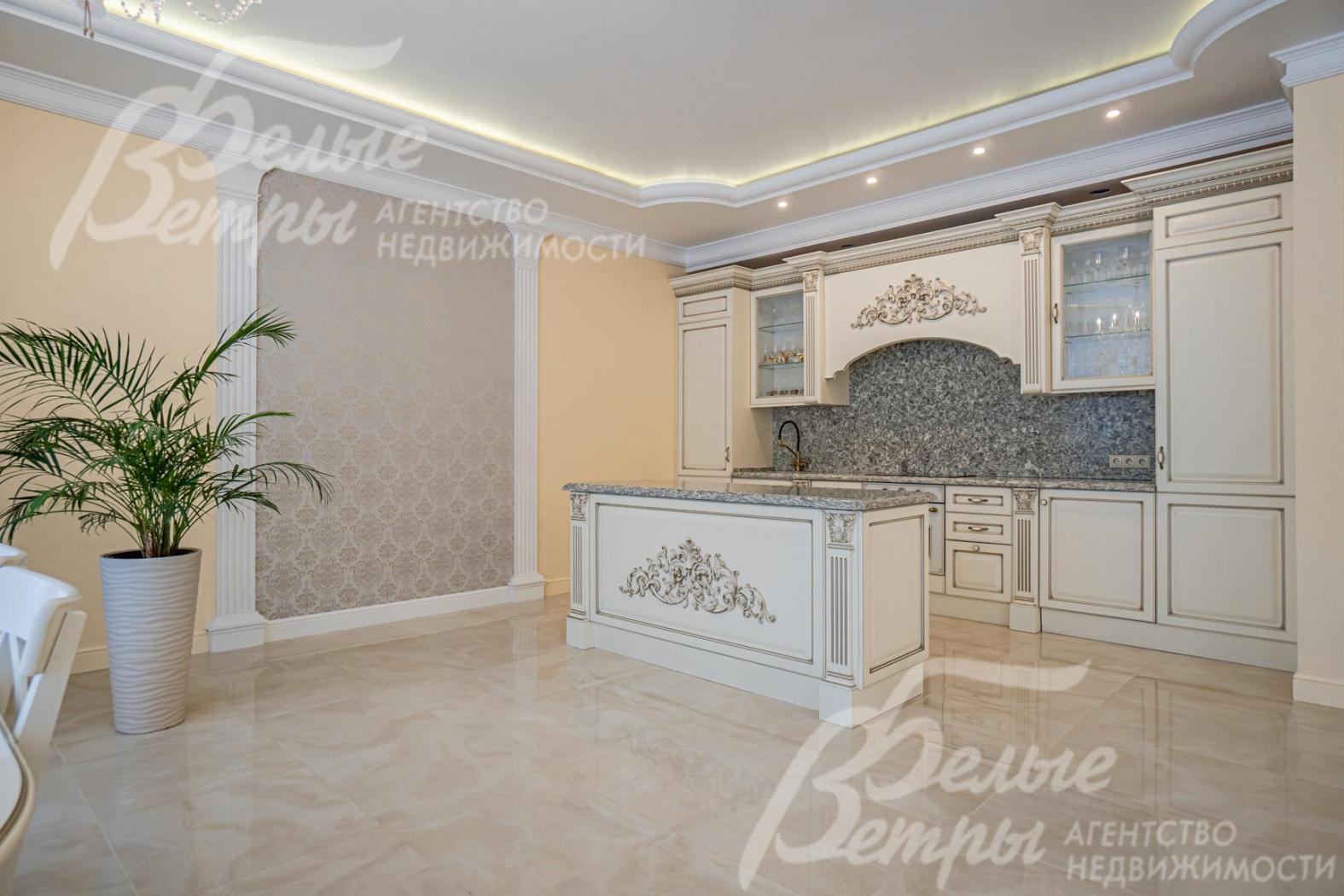 Кухня с островом, фасады из массива дерева, кремового цвета, со сложным резным карнизом (золотая резьба) и филенками из дерева