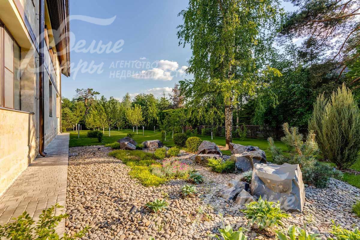 На участке множество деревьев, декоративных кустарников и цветников