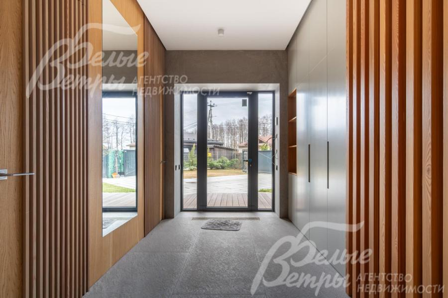 В прихожей есть гардеробная, большое зеркало, установлена входная дверь с тремя полноразмерными стёклами