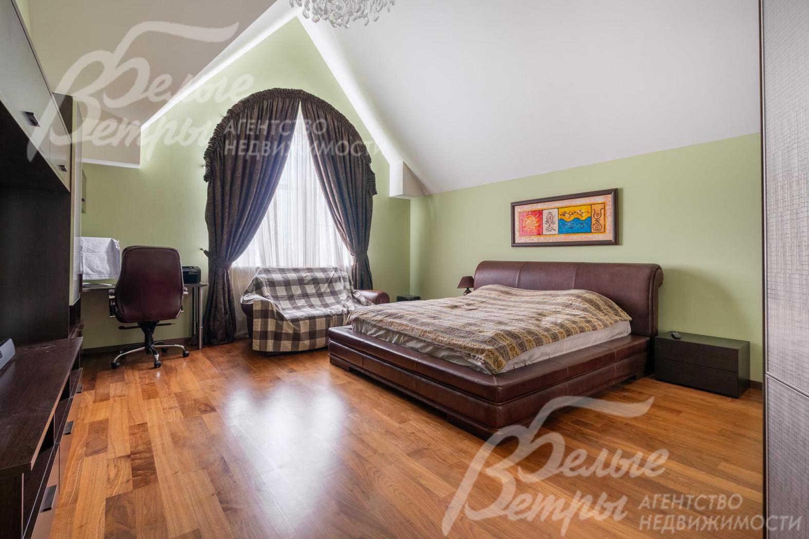 Одна из спален на втором этаже с кроватью, диваном и рабочим местом