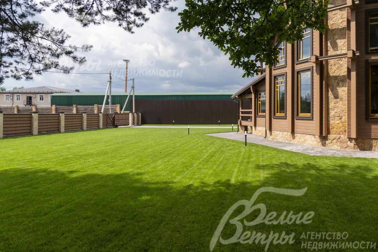 Перед домом - большая лужайка с безупречным газоном. Вокруг дома - широкая отмостка из брусчатки и освещение 