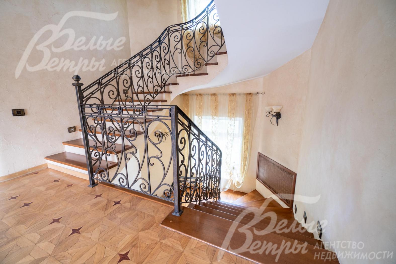 На второй этаж ведёт лестница с отделкой ступеней массивом ореха и кованым ограждением
