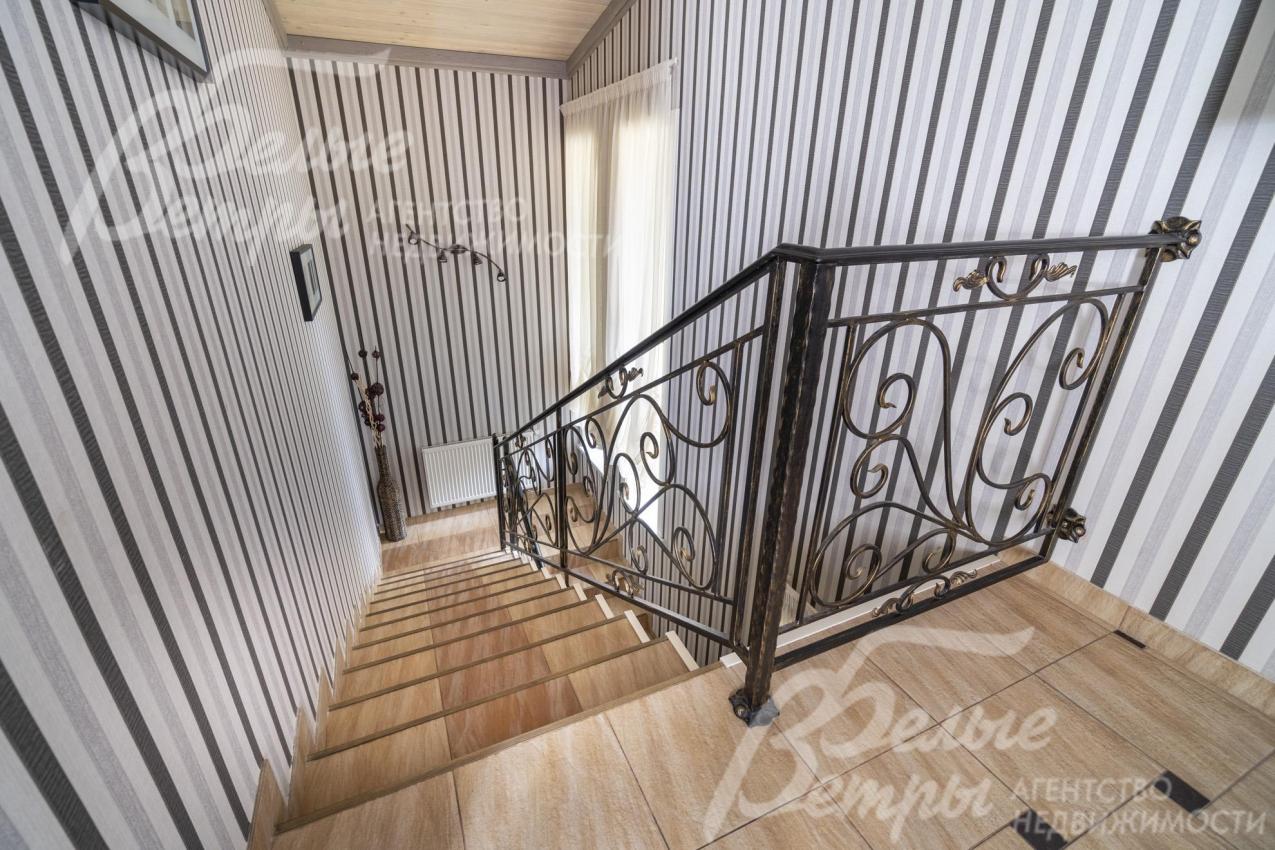 На второй этаж гостевого дома ведёт лестница, отделанная керамогранитом, с коваными перилами