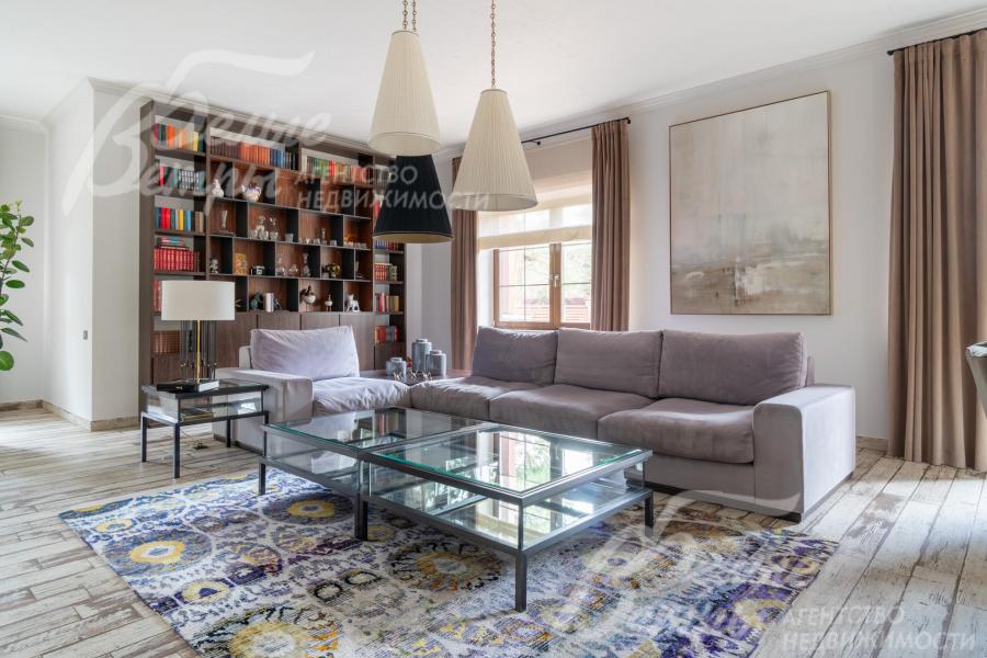 В гостиной - уютная диванная зона с мини-библиотекой. Дом украшают живописные полотна известных художников.