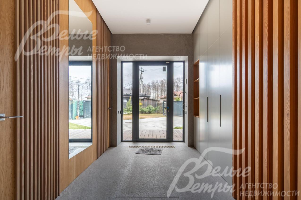 В прихожей есть гардеробная, большое зеркало, установлена входная дверь с тремя полноразмерными стёклами