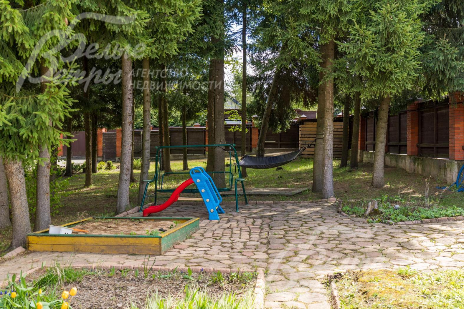 На участке в окружении вековых деревьев обустроена детская площадка