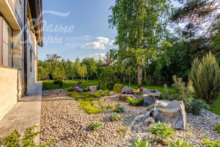 На участке множество деревьев, декоративных кустарников и цветников