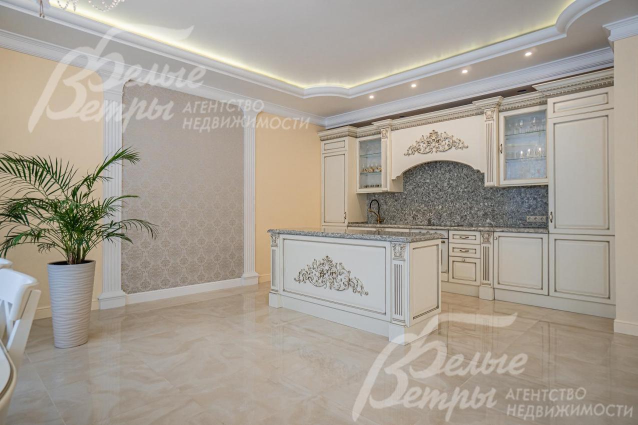 Кухня с островом, фасады из массива дерева, кремового цвета, со сложным резным карнизом (золотая резьба) и филенками из дерева