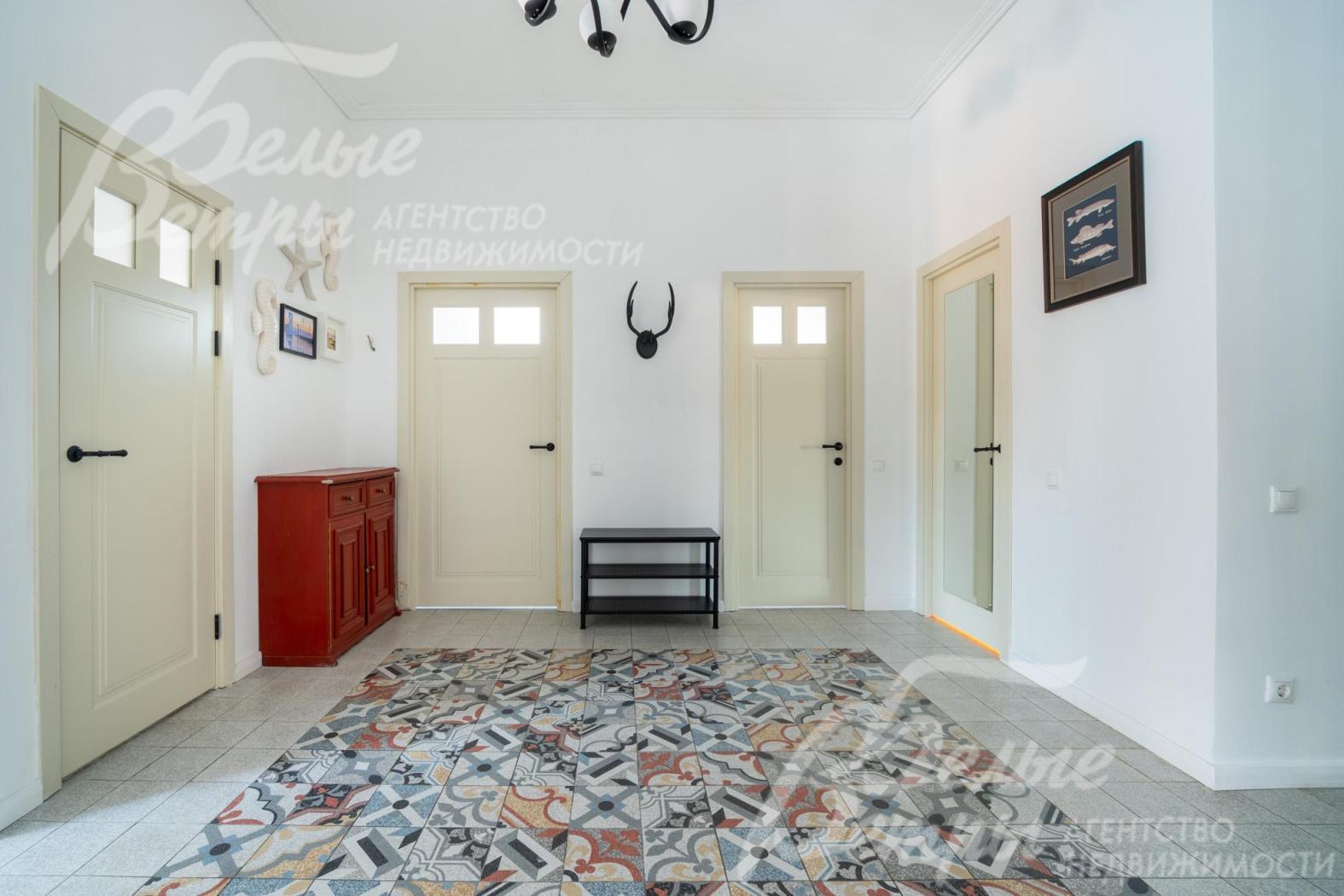 В просторном холле на первом этаже уложена декоративная плитка-ковёр с геометрическим узором