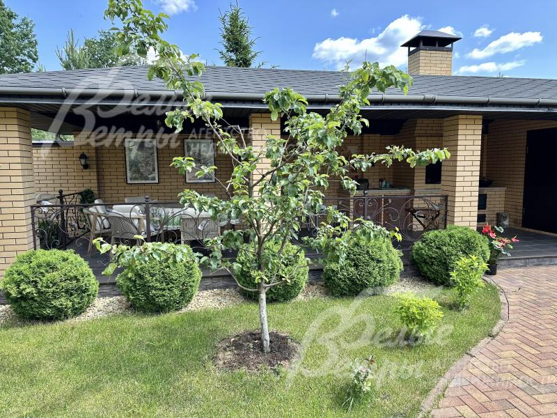 Кирпичные столбы соединяют кованные черные перила в винтажном стиле.