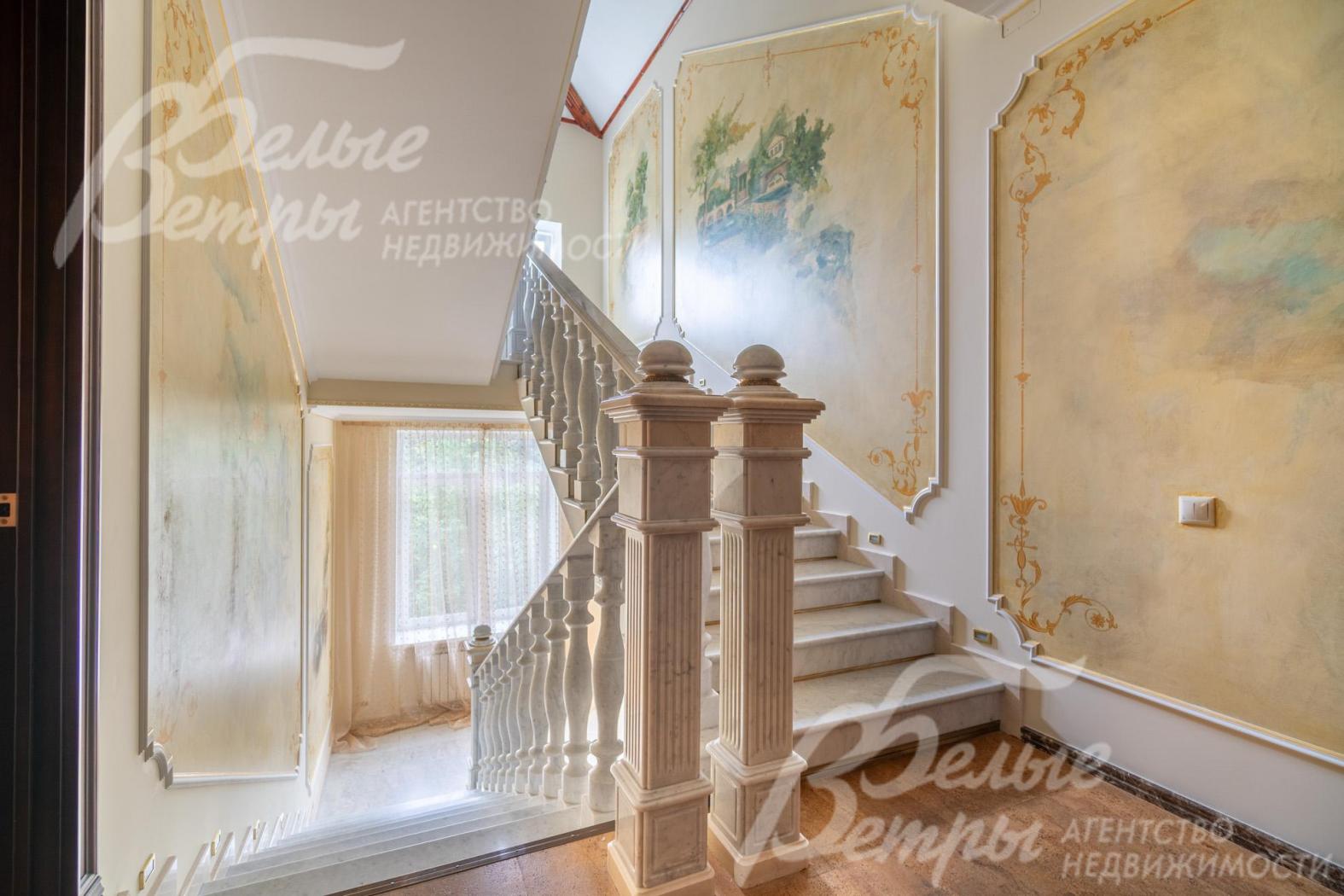 Стены вдоль лестницы украшены панно в классическом стиле