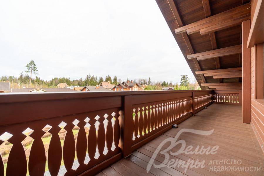 Лоджия мастер-спальни в стиле шале с резными деревянными перилами и тёплыми коричневыми оттенками