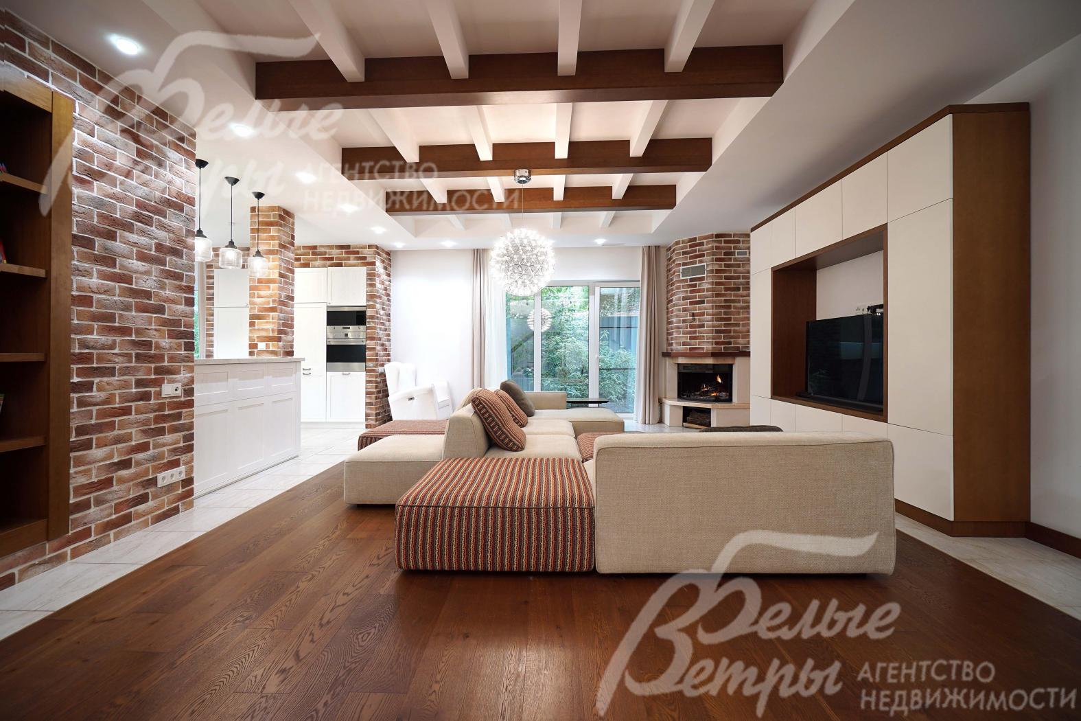 Гостиная с акцентными стенами с отделкой "под кирпич" и декоративными деревянными балками на потолке