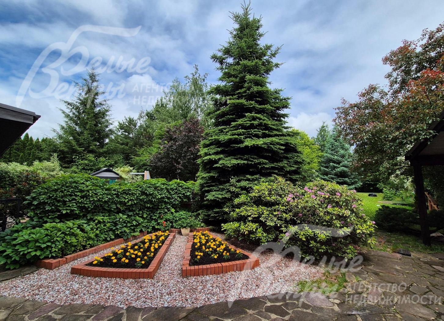 Благоустроенный участок со взрослыми лесными и декоративными деревьями и растениями.