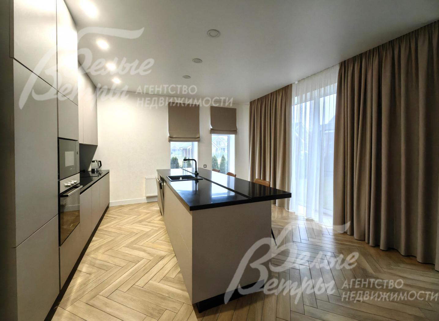 Кухонный гарнитур с островом и барными стульями.