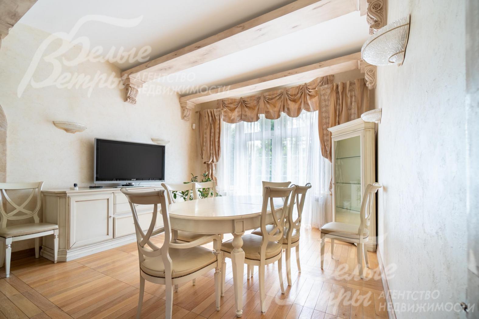 Столовая с обеденной группой, мебелью и телевизором. Большое окно наполняет гостиную дневным светом