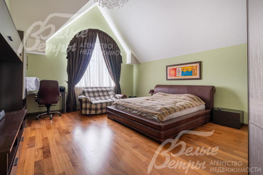 Одна из спален на втором этаже с кроватью, диваном и рабочим местом