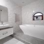 Стильный санузел в серо-белой палитре, белая ванна подчёркивает статусность интерьера